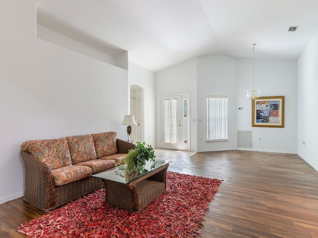 living room with hardwood / wood-style floors, a chandelier, and vaulted ceiling