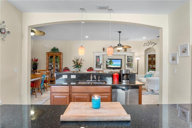 kitchen featuring stainless steel dishwasher, hanging light fixtures, dark stone counters, and sink