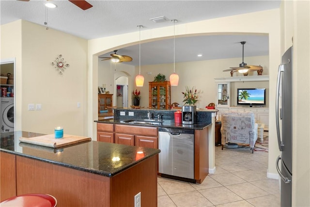 kitchen featuring dark stone counters, pendant lighting, sink, and stainless steel appliances