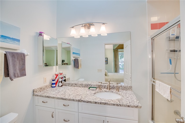 bathroom with toilet, vanity, and a shower with shower door