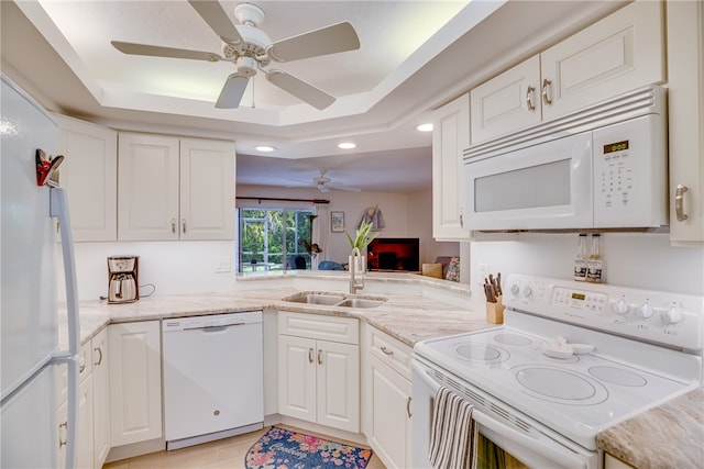 kitchen featuring a tray ceiling, white appliances, and white cabinets