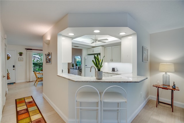 kitchen with white refrigerator, kitchen peninsula, light hardwood / wood-style floors, and ceiling fan