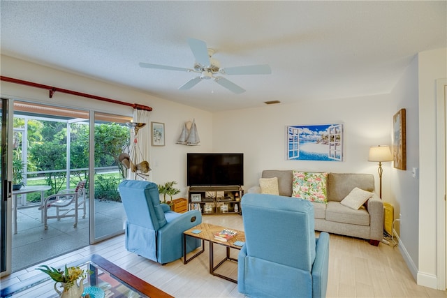 living room featuring ceiling fan, a textured ceiling, and light hardwood / wood-style flooring