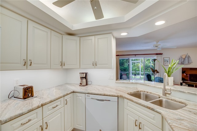 kitchen featuring dishwasher, sink, ceiling fan, a raised ceiling, and white cabinetry