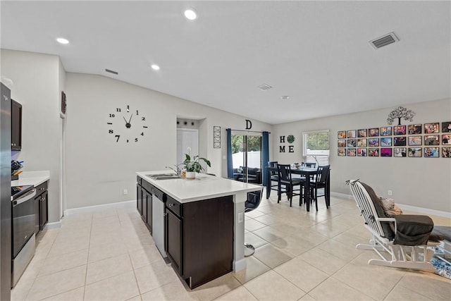 kitchen featuring lofted ceiling, sink, an island with sink, light tile patterned flooring, and stainless steel appliances