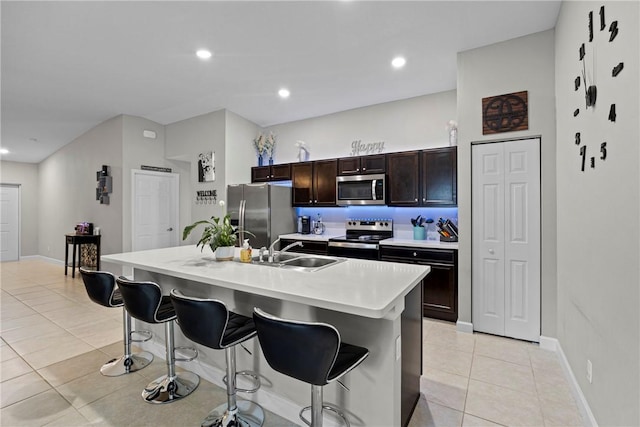 kitchen with appliances with stainless steel finishes, sink, a kitchen breakfast bar, and an island with sink