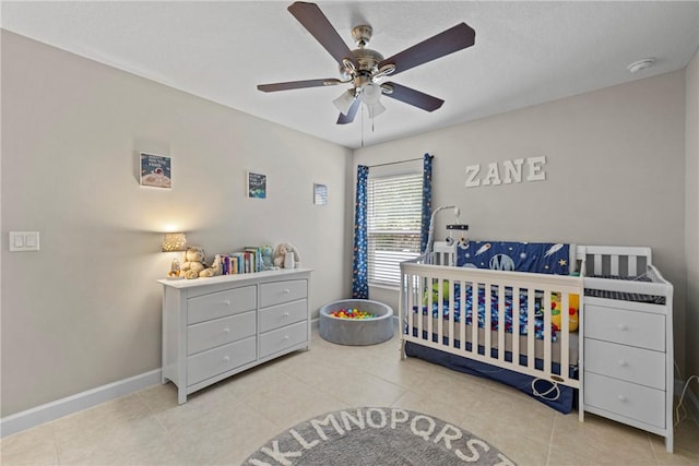 bedroom featuring ceiling fan, light tile patterned floors, and a nursery area