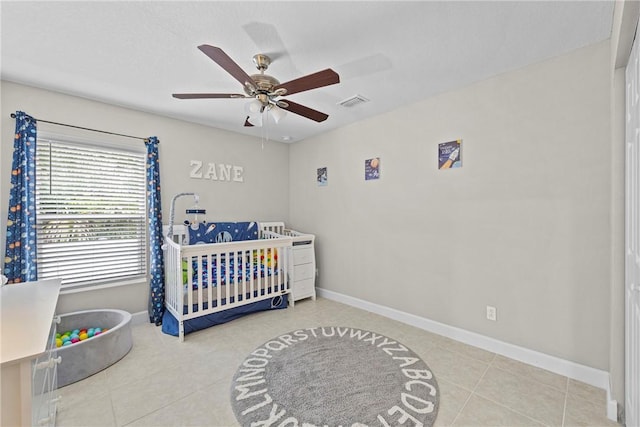 bedroom featuring tile patterned flooring, ceiling fan, and a crib