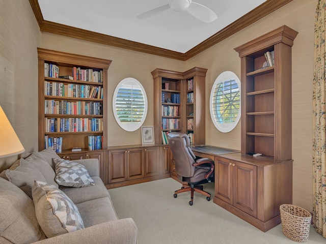 home office featuring built in desk, light colored carpet, ceiling fan, and crown molding