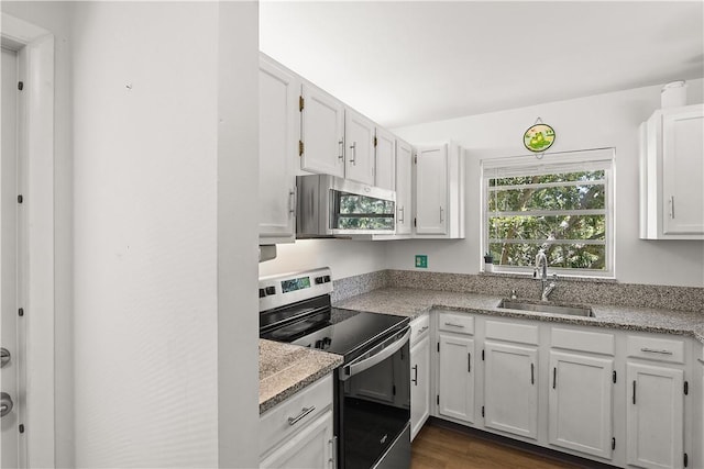 51 Woodland Dr Unit 207, Vero Beach, FL 32962 - kitchen with appliances with stainless steel finishes, white cabinets, dark wood-type flooring, and light stone countertops