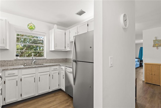 51 Woodland Dr Unit 207, Vero Beach, FL 32962 - kitchen with appliances with stainless steel finishes, white cabinets, wood finished floors, and light stone countertops