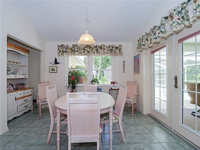 dining space with a wealth of natural light, tile patterned floors, and lofted ceiling