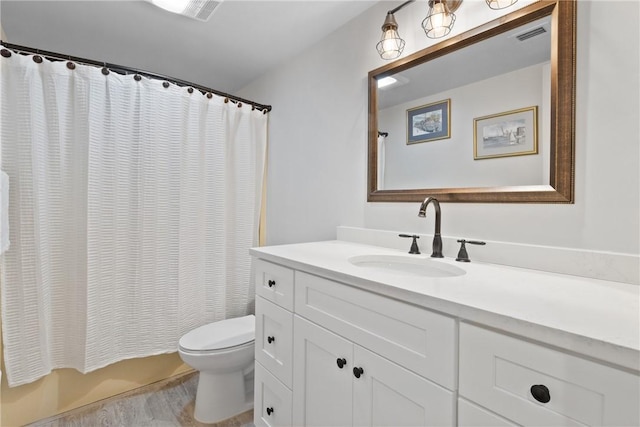 bathroom featuring toilet, visible vents, wood finished floors, and vanity