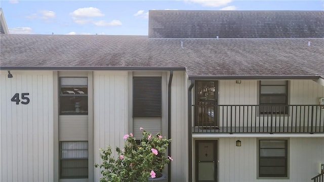 view of exterior entry featuring a shingled roof