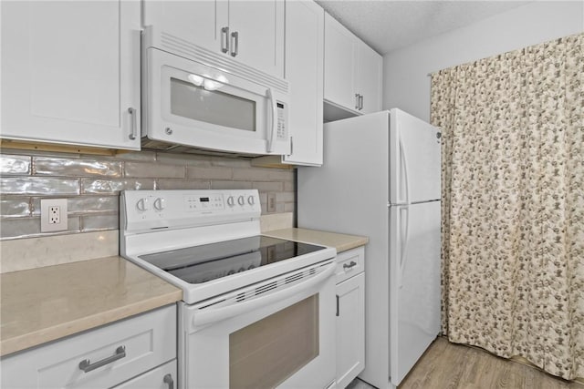 kitchen with white cabinetry, light wood-type flooring, white appliances, and decorative backsplash