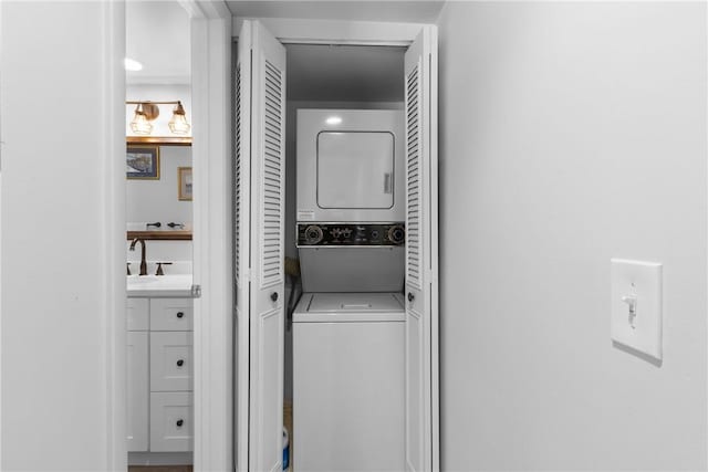 clothes washing area featuring a sink, stacked washer and clothes dryer, and laundry area