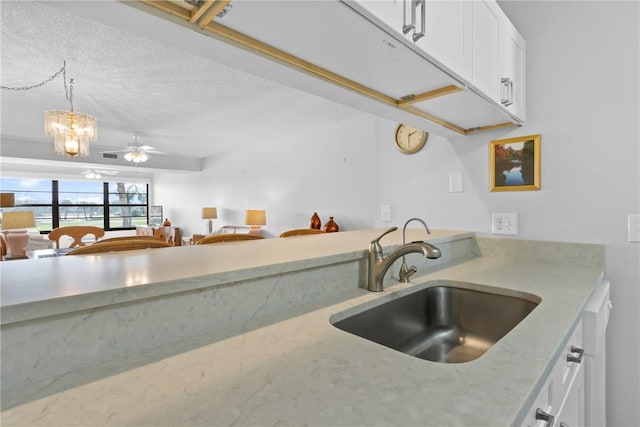 kitchen featuring a ceiling fan, pendant lighting, white cabinetry, and a sink