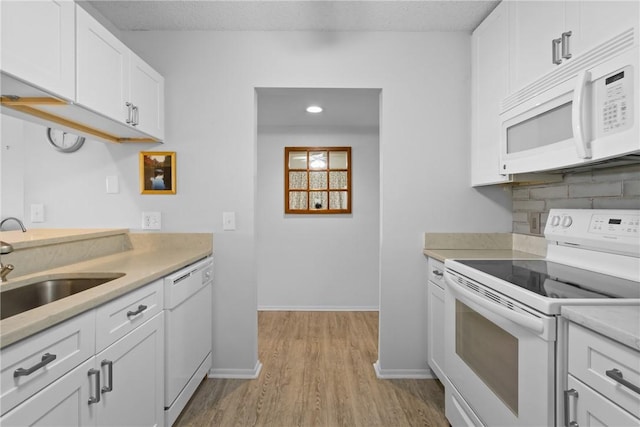 kitchen with white appliances, a sink, light countertops, white cabinetry, and backsplash