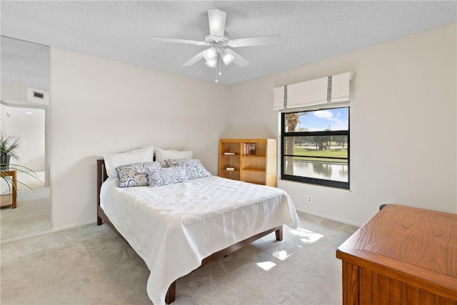 bedroom with a ceiling fan, light carpet, a textured ceiling, and baseboards