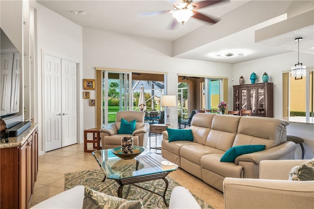 tiled living room featuring ceiling fan with notable chandelier