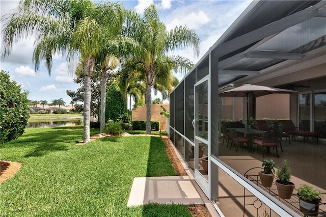 view of yard with glass enclosure, a patio area, and a water view