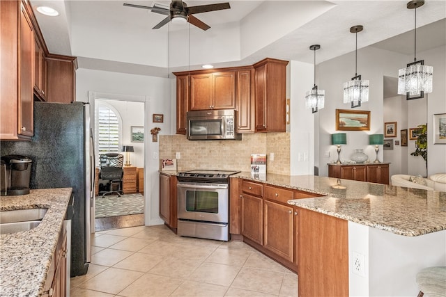 kitchen featuring kitchen peninsula, decorative light fixtures, light tile patterned floors, ceiling fan with notable chandelier, and appliances with stainless steel finishes