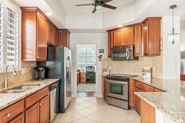 kitchen featuring hanging light fixtures, sink, ceiling fan, appliances with stainless steel finishes, and light stone counters