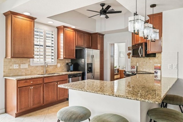 kitchen with a breakfast bar, sink, appliances with stainless steel finishes, decorative light fixtures, and kitchen peninsula