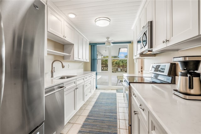 kitchen with stainless steel appliances, white cabinets, sink, light tile patterned floors, and ceiling fan