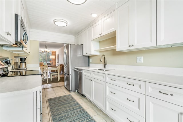 kitchen with stainless steel appliances, light tile patterned flooring, white cabinetry, and sink