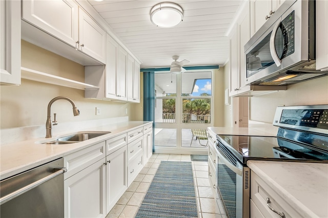 kitchen with stainless steel appliances, light tile patterned flooring, white cabinetry, and sink