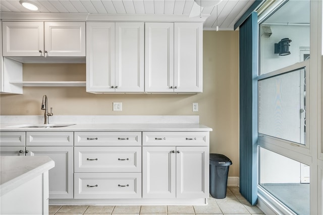 kitchen with white cabinets, light tile patterned flooring, and sink