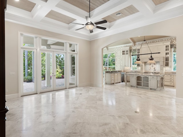 unfurnished living room featuring beamed ceiling, a healthy amount of sunlight, crown molding, and coffered ceiling