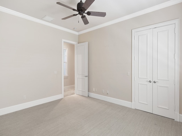 unfurnished bedroom featuring light colored carpet, ceiling fan, crown molding, and a closet