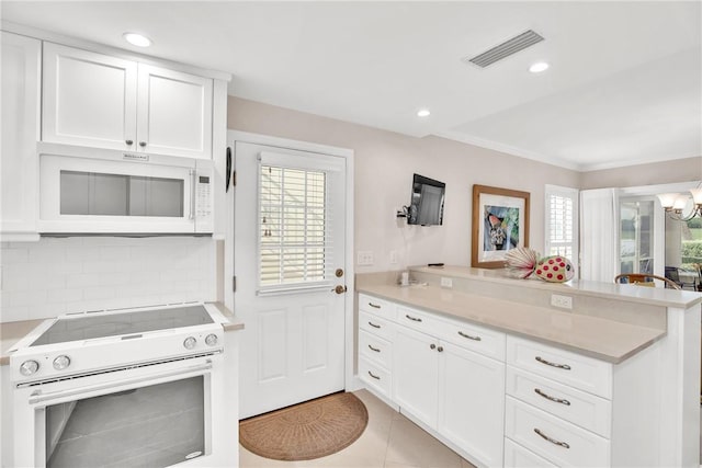 kitchen with light tile patterned floors, kitchen peninsula, white cabinets, and stainless steel electric range oven