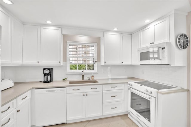 kitchen featuring sink, white appliances, white cabinetry, tasteful backsplash, and light tile patterned flooring