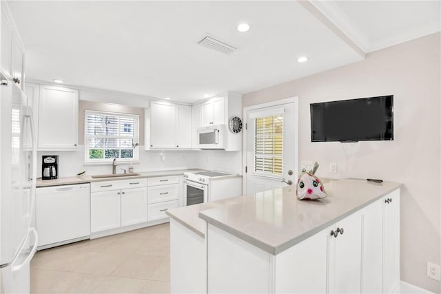 kitchen featuring sink, light tile patterned floors, kitchen peninsula, white appliances, and white cabinets