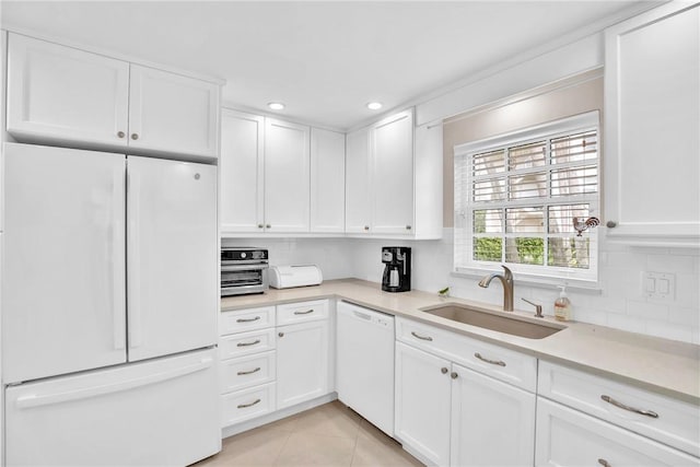 kitchen with sink, white appliances, light tile patterned floors, white cabinets, and decorative backsplash