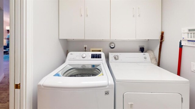 clothes washing area with cabinets and independent washer and dryer