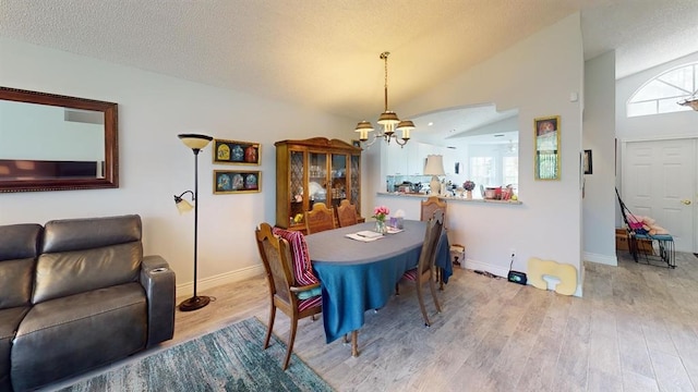 dining space featuring light wood-type flooring, a textured ceiling, high vaulted ceiling, and an inviting chandelier