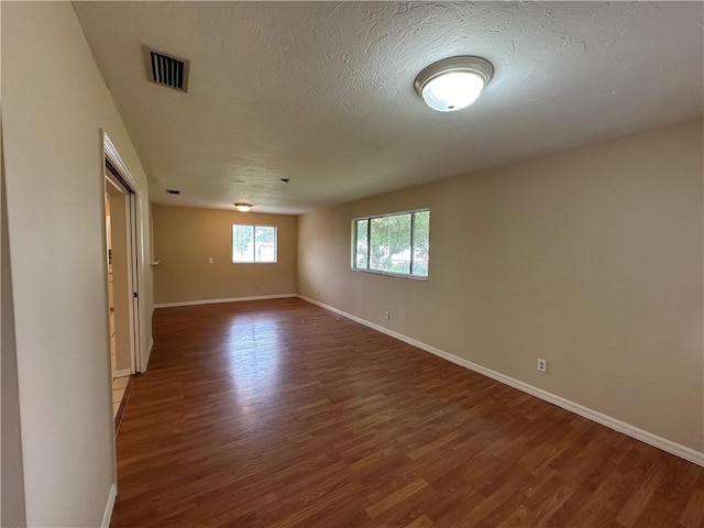 spare room with dark wood-type flooring and a textured ceiling