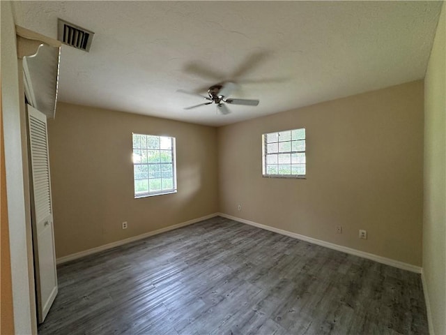 unfurnished bedroom with multiple windows, dark hardwood / wood-style floors, and ceiling fan