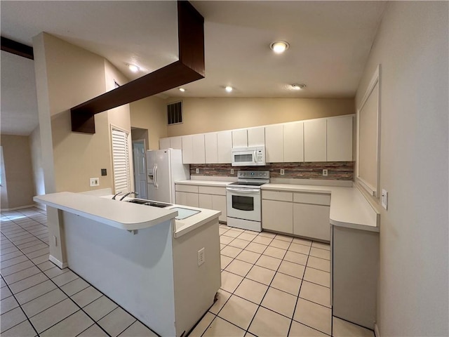 kitchen with tasteful backsplash, lofted ceiling, white cabinets, kitchen peninsula, and white appliances