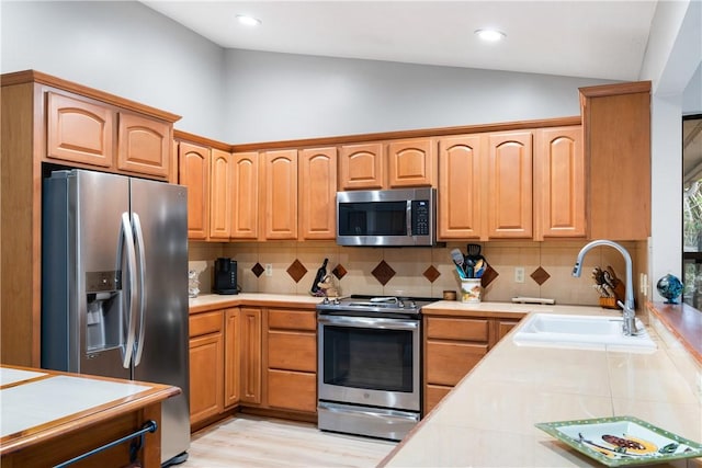 kitchen with appliances with stainless steel finishes, sink, light hardwood / wood-style floors, and decorative backsplash