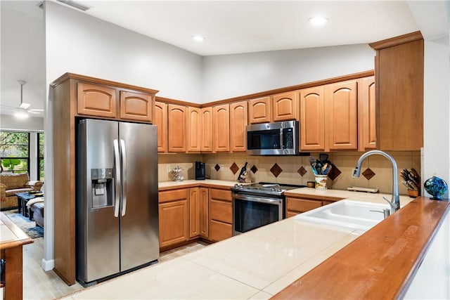 kitchen with sink, tasteful backsplash, high vaulted ceiling, stainless steel appliances, and light hardwood / wood-style floors