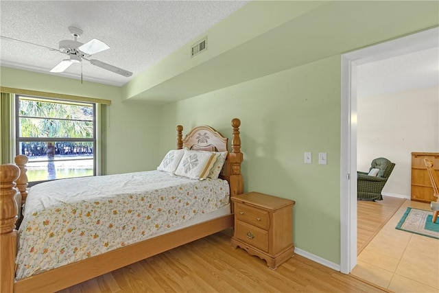12 Plantation Dr Unit 205, Vero Beach, FL 32966 - bedroom with light wood-style flooring, a textured ceiling, and ceiling fan