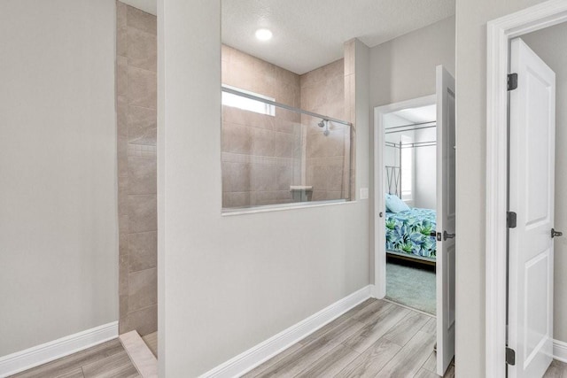 bathroom with hardwood / wood-style flooring, a tile shower, and a textured ceiling