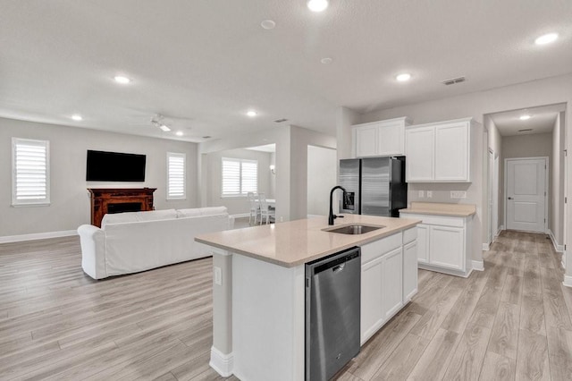 kitchen featuring light wood-type flooring, stainless steel appliances, sink, a center island with sink, and white cabinetry