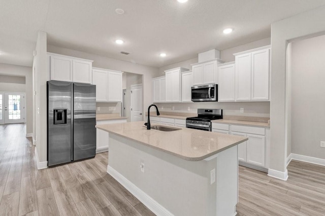 kitchen with white cabinetry, sink, light hardwood / wood-style floors, a center island with sink, and appliances with stainless steel finishes