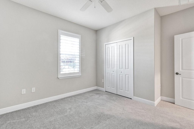 unfurnished bedroom with light carpet, a closet, and ceiling fan